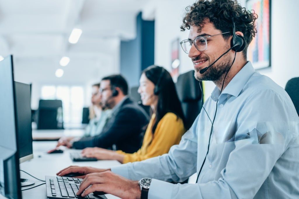 Rooftop call agent wearing a headset speaking with a homeowner at a desk