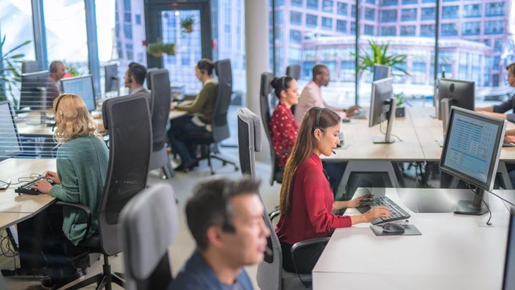 Open-plan call centre floor with agents working at desks wearing headsets